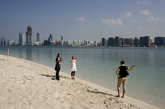 A tourist takes a photograph in front of the skyline of Abu Dhabi.