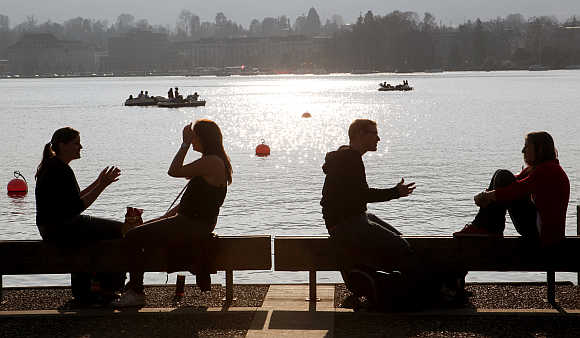 People enjoy the sunny spring weather as they sit on the banks of Lake Zurich.