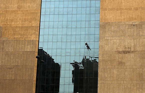 A worker cleans the glass exterior of a building in the commercial hub of New Delhi.