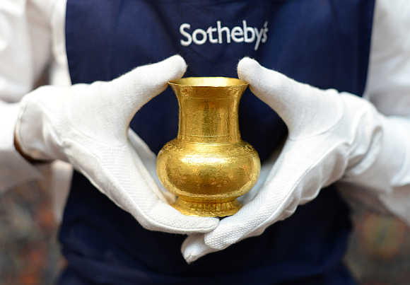 A member of Sotheby's staff holds a 14th century central Asian gold cup with an estimated value of $48,600-$81,000.