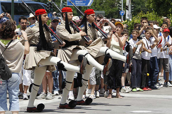 Tourists watch a performance of the Changing of the Guard Ceremony in front of the Greek Parliament Building in Athens.