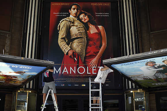 Workers prepare billboards at a cinema in downtown Madrid, Spain.