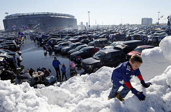 Decklan Corcoran climbs on a pile of snow at MetLife Stadium before the NFL football game between the New York Giants and the Miami Dolphins in East Rutherford, New Jersey.