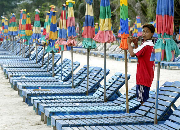 A man bundles up giant umbrellas along Patong Beach in Phuket.