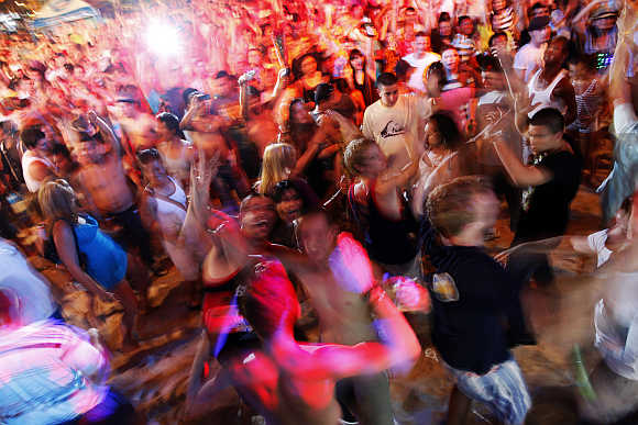 Tourists dance to electronic music during an open-air party at Patong Beach in Phuket.