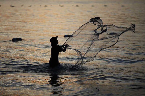 A fisherman casts his net at Patong Beach in Phuket.