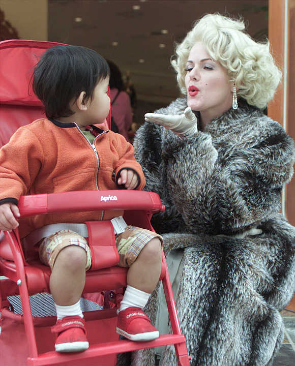 A Marylin Monroe lookalike blows a kiss to a boy in a baby buggy in Osaka, Japan.