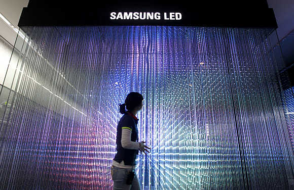 An employee of Samsung Electronics walks past LED lighting drums displayed at a showroom in Seoul.