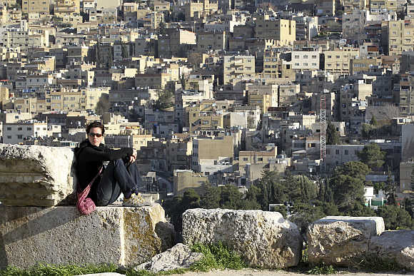 A tourist looks towards a mountain while sitting at the Amman Citadel.
