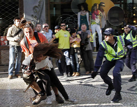 A policeman strikes AFP photojournalist Patricia Melo during the Portuguese general strike in Lisbon.