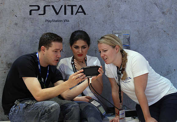 Visitors play with Playstation PS Vita at the Sony Playstation exhibition stand in Cologne, Germany.