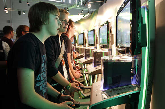 Visitors play the Xbox at the Microsoft exhibition stand in Cologne, Germany.