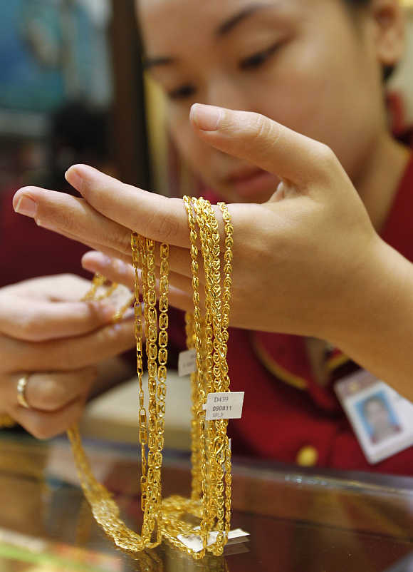 An employee looks at gold jewellery at a shop in Hanoi, Vietnam.