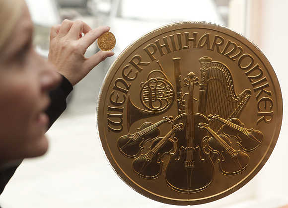 A woman displays a small gold coin next to Europe's largest gold coin in a shop in Vienna, Austria.
