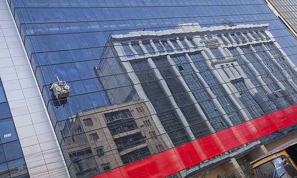 A window cleaner in a gondola cleans glass facade of a building in a business district in Karachi.