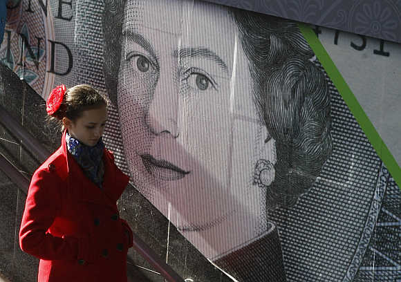A woman passes by an outdoor advert with an image of the British pound bank note in central Kiev, Ukraine.