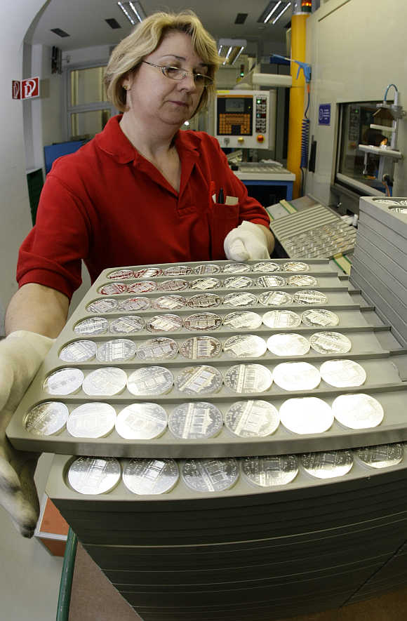 A worker at the Austrian Mint holds a tray of silver Vienna Philharmonic Bullion coins at the Mint's headquarters in Vienna, Austria.