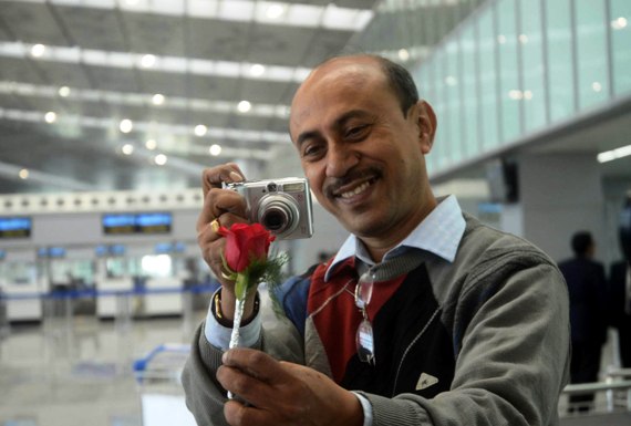 A passenger takes photograph of the rose that he got as a welcome gift at the new Kolkata airport.