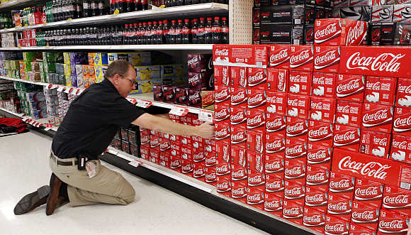 An employee arranges cartons of Coca-Cola at a store in Alexandria, Virginia, United States.