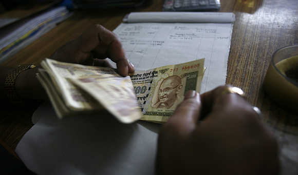 An employee counts currency notes at a cash counter inside a bank in Agartala, capital of Tripura.