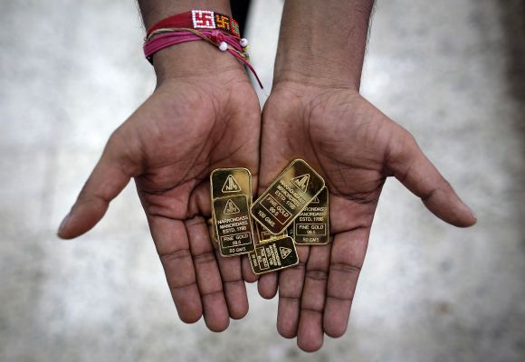 An employee poses with gold biscuits inside a jewellery showroom in Mumbai.