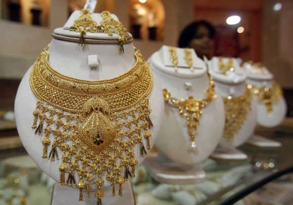 A saleswoman stands behind the showcased gold necklaces at a jewellery showroom in Agartala.