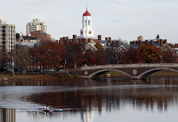A pair of rowers are seen in the Charles River as Harvard University is reflected in the water in Cambridge, Massachusetts.