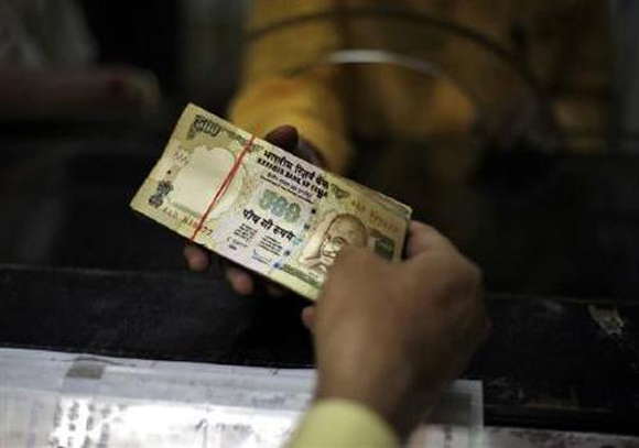 A bank employee counts rupee notes.