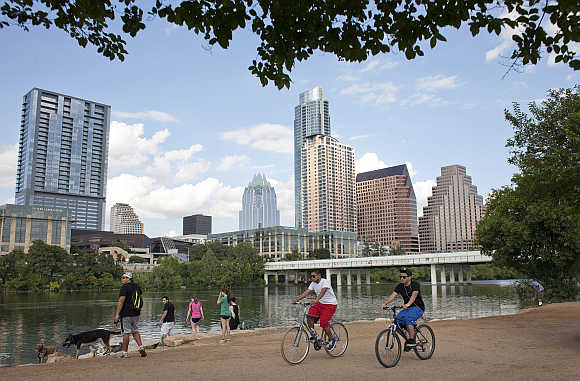 Cyclists pass beneath the downtown skyline on the hike and bike trail on Lady Bird Lake in Austin, Texas, United States.