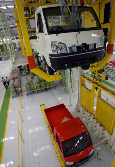 Employees walks past an assembly line of Maxximo, a light commercial vehicle, at a new plant of Mahindra and Mahindra in Chakan.