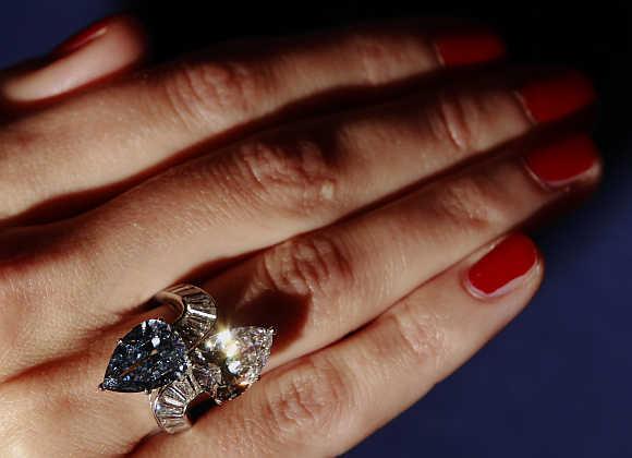 A Bonhams employee poses with the Bvlgari crossover ring set with 3.72 carat fancy vivid blue diamond and 3.93 carat diamond at Bonhams auction house in London.