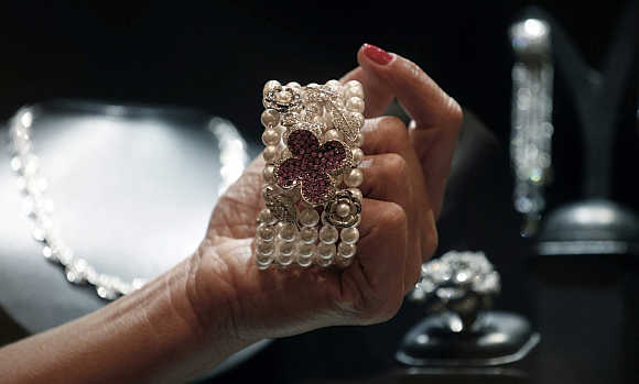 A shop assistant shows a bracelet from Brazilian designer Mauricio Monteiro, containing a selection of large pink sapphires, pearls and diamonds, at the Iguatemi mall in Sao Paulo, Brazil.