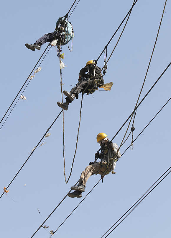 Labourers remove kites tangled up in electric power cables in Ahmedabad.
