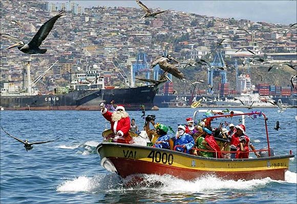 Ruben Torres, dressed in a Santa Claus outfit, and fishermen wave to people from a boat on Christmas Eve along the coast of Valparaiso city, about 121 km (75 miles) northwest of Santiago.