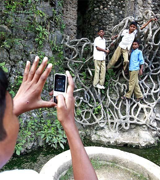  A schoolboy uses his cell phone to take a picture of classmates hanging onto cement roots at Nek Chand's Rock Garden in Chandigarh.