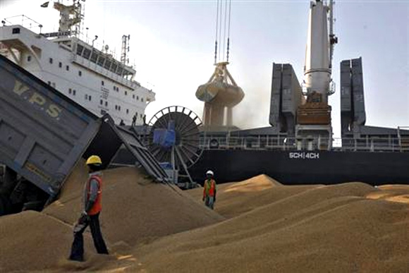 A dumper unloads wheat as a crane loads onto a cargo ship at the Mundra port in Gujarat.