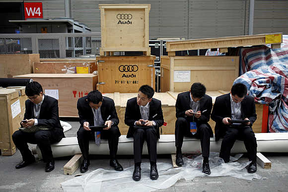 Men sit next to boxes of German carmaker Audi in Shanghai, China.