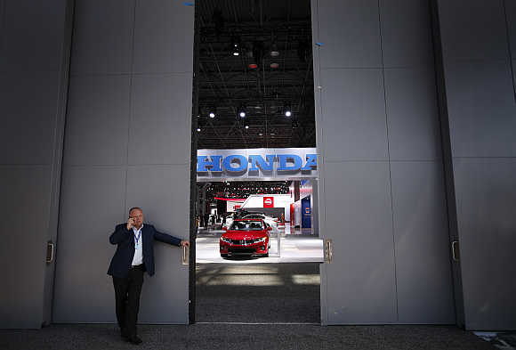 A man uses a mobile phone while standing outside a Honda display in New York.