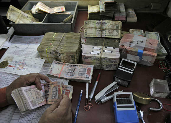 An employee counts rupeee notes at a cash counter inside a bank in New Delhi.