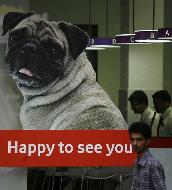 A man walks past a logo of Vodafone displayed on a shop in Mumbai.