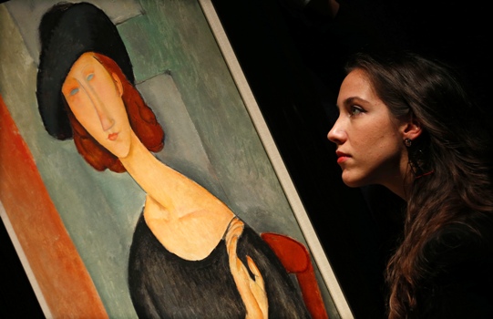 A worker poses with 'Jeanne Hebuterne (au chapeau)' from 1919 by Amedeo Modigliani, at Christie's auction house in London.