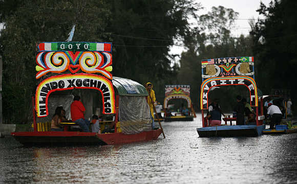 A man rows a Trajinera (boat) along the Xochimilco canals in Mexico City.