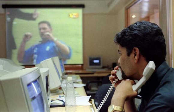 A stock broker watches England play Sri Lanka in the inugural World Cup match as he trades on the phone in Mumbai, May 14.