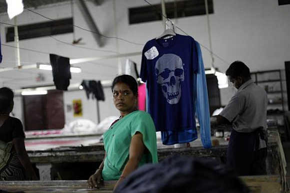 An employee stands next to a newly dyed T-shirt at the Estee garment factory in Tirupur, Tamil Nadu.