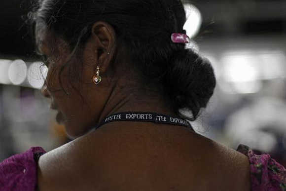 An employee wears a lanyard with the company's name printed on it as she works at the Estee garment factory in Tirupur, Tamil Nadu.