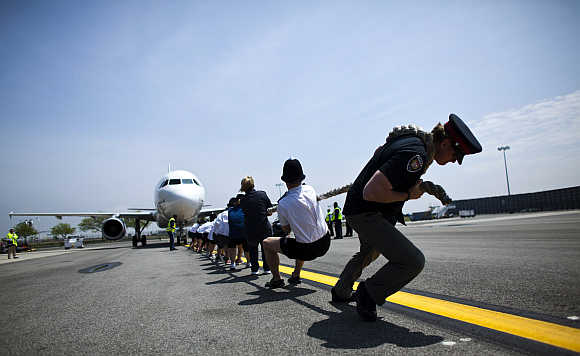 Members of the London Metropolitan Police Service tug an Airbus A320 jet for 100 feet during a race at John F Kennedy International Airport in New York.