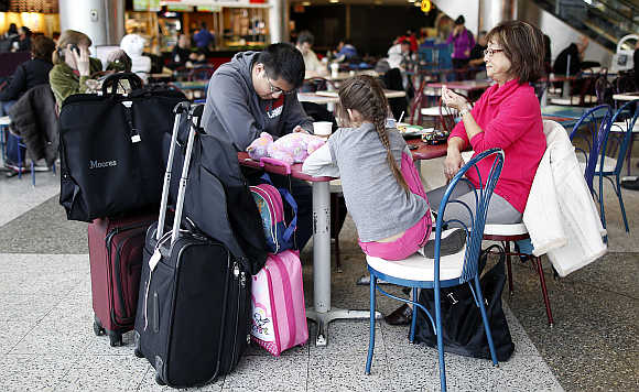 A family sits a table in the food court of LaGuardia Airport in New York.
