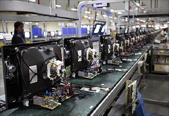 A worker at LG Electronics India Pvt Ltd. checks television sets on an assemble line inside a factory at Greater Noida in Uttar Pradesh.