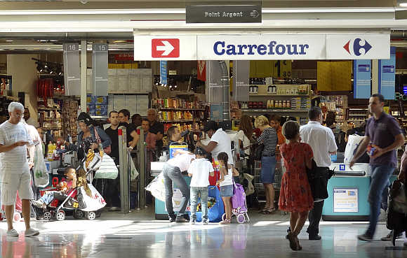Customers queue at cash registers in a Carrefour supermarket in Montreuil near Paris.