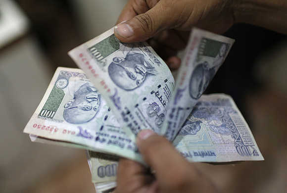 An employee counts rupee notes inside a private money exchange office in New Delhi.